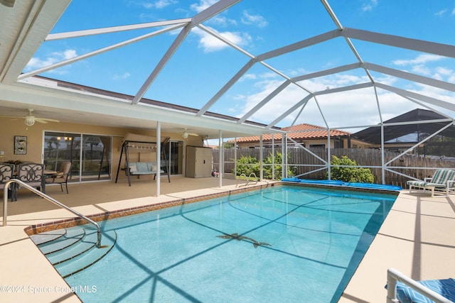 view of swimming pool with a patio area, a storage shed, ceiling fan, and glass enclosure