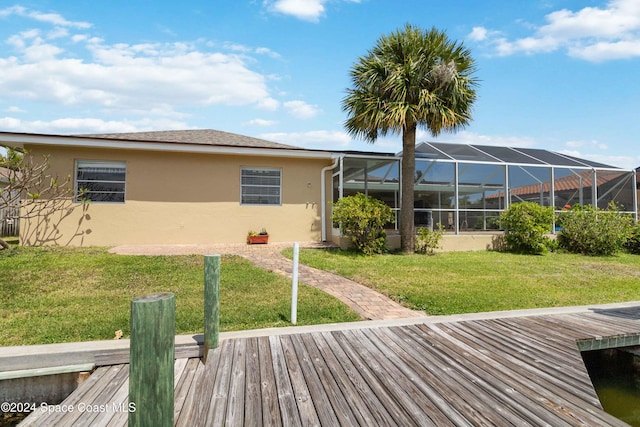 back of house featuring a deck, a lawn, and a lanai