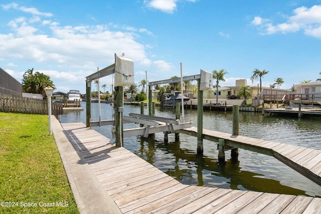 view of dock with a water view and a lawn