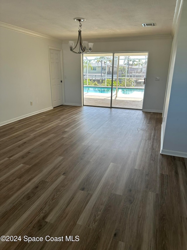 interior space with dark wood-type flooring, ornamental molding, and an inviting chandelier