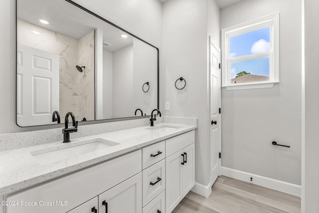 bathroom featuring vanity, a tile shower, and wood-type flooring