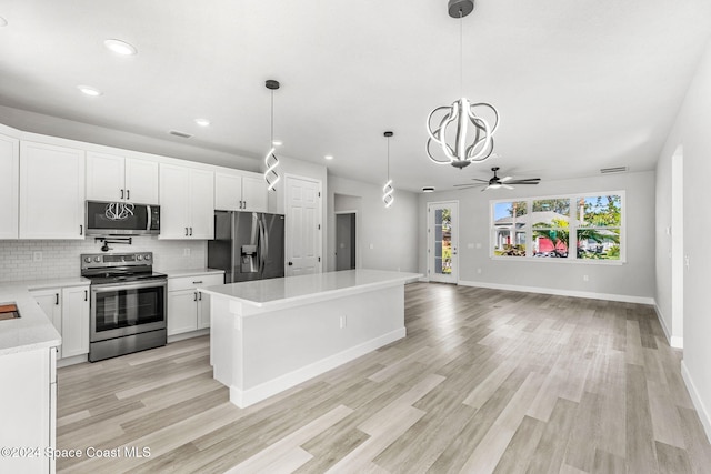 kitchen featuring appliances with stainless steel finishes, light wood-type flooring, ceiling fan, pendant lighting, and white cabinets