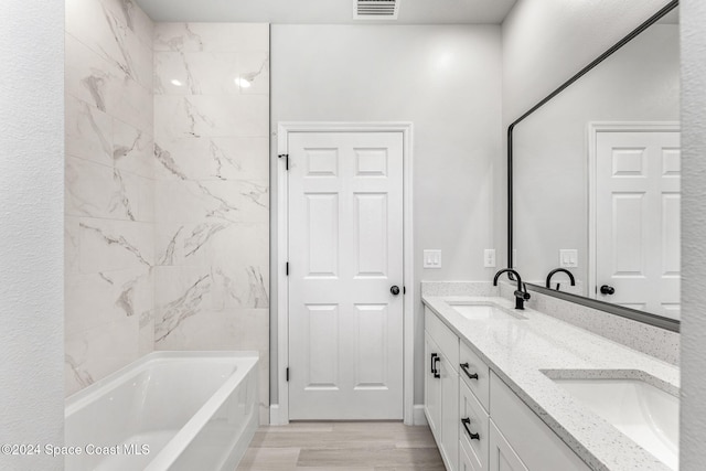 bathroom with hardwood / wood-style floors, vanity, and tiled shower / bath