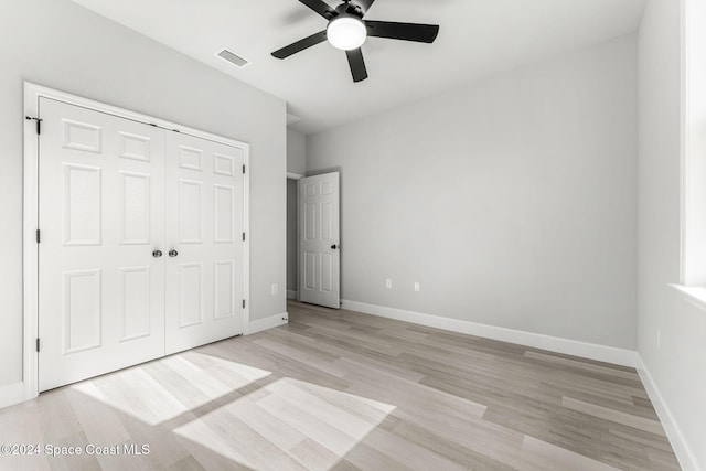 unfurnished bedroom with a closet, light hardwood / wood-style floors, and ceiling fan