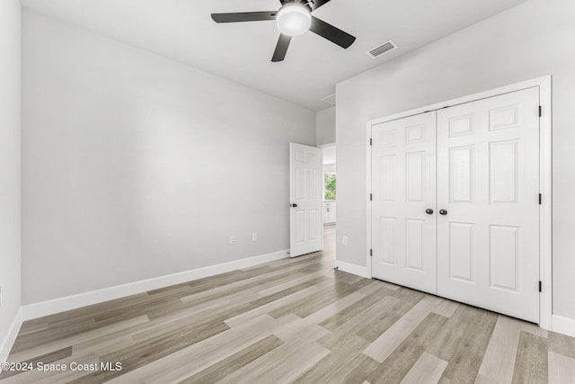 unfurnished bedroom featuring ceiling fan, light hardwood / wood-style floors, and a closet