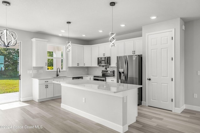 kitchen featuring appliances with stainless steel finishes, sink, light hardwood / wood-style flooring, white cabinets, and a center island