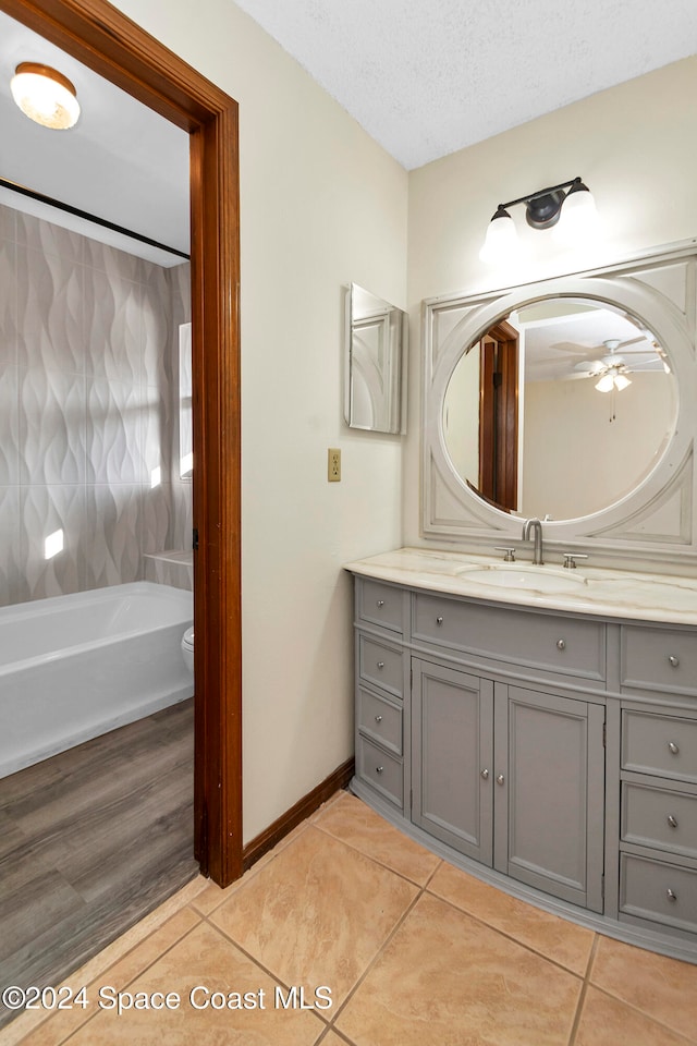 bathroom featuring tile patterned flooring, ceiling fan, a textured ceiling, vanity, and toilet