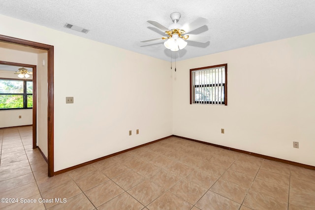 unfurnished room with a wealth of natural light, ceiling fan, and a textured ceiling