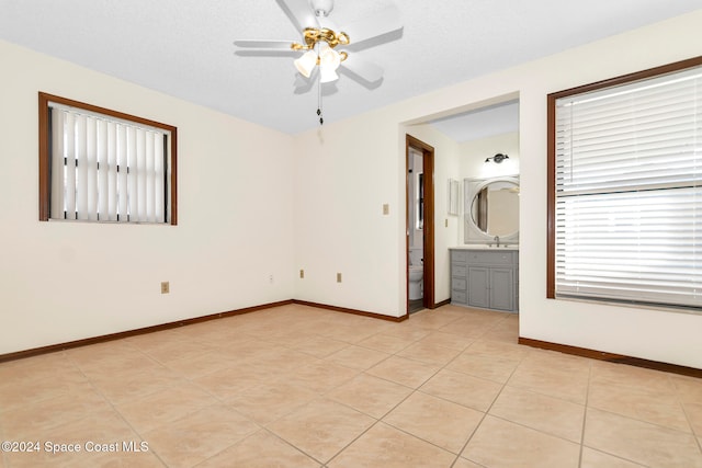 tiled spare room featuring a wealth of natural light, sink, ceiling fan, and a textured ceiling