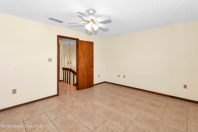 tiled empty room with ceiling fan and a textured ceiling