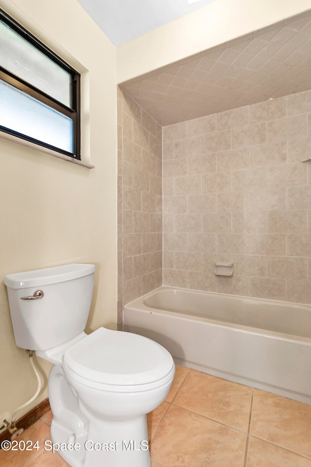 bathroom with toilet, tiled shower / bath, and tile patterned floors