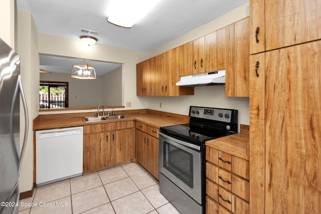 kitchen featuring butcher block counters, sink, light tile patterned floors, pendant lighting, and appliances with stainless steel finishes