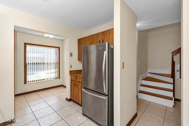 kitchen featuring stainless steel refrigerator, a textured ceiling, and light tile patterned floors