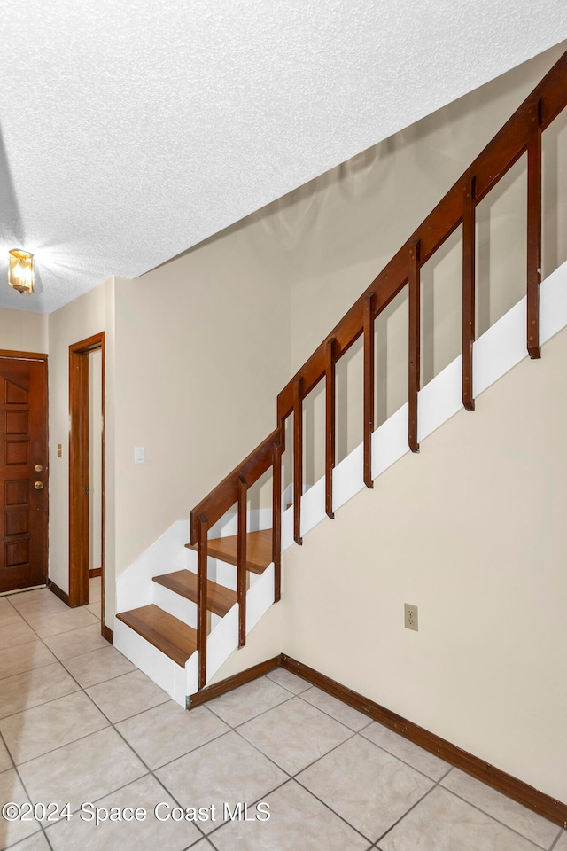 stairs with tile patterned flooring and a textured ceiling