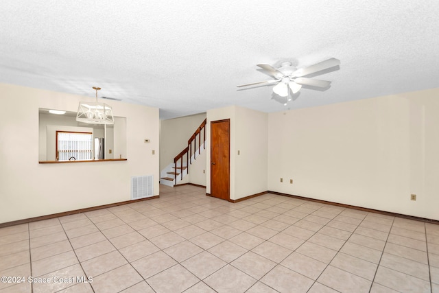 tiled spare room featuring ceiling fan with notable chandelier and a textured ceiling