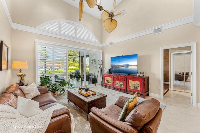 living room featuring ornamental molding, light tile patterned floors, a high ceiling, and ceiling fan