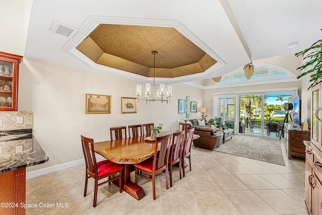 tiled dining space with ornamental molding, a chandelier, and a tray ceiling