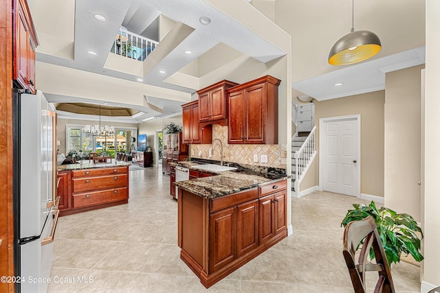 kitchen featuring dark stone counters, crown molding, decorative light fixtures, a chandelier, and white fridge