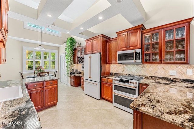 kitchen featuring light stone countertops, light tile patterned flooring, pendant lighting, high quality appliances, and sink