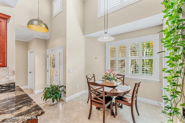 tiled dining area with ornamental molding and a high ceiling