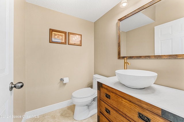 bathroom with vanity, toilet, tile patterned floors, and a textured ceiling