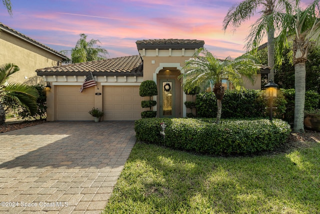 mediterranean / spanish-style house with a garage and a lawn