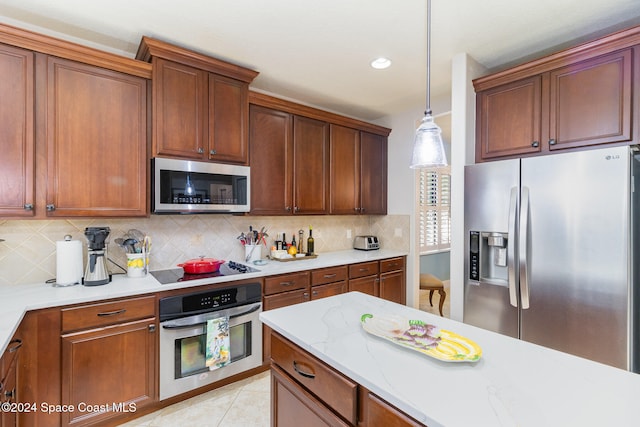 kitchen with appliances with stainless steel finishes, hanging light fixtures, backsplash, and light tile patterned floors