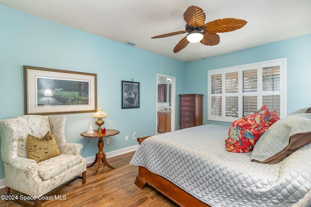 bedroom with a ceiling fan, visible vents, wood finished floors, baseboards, and connected bathroom