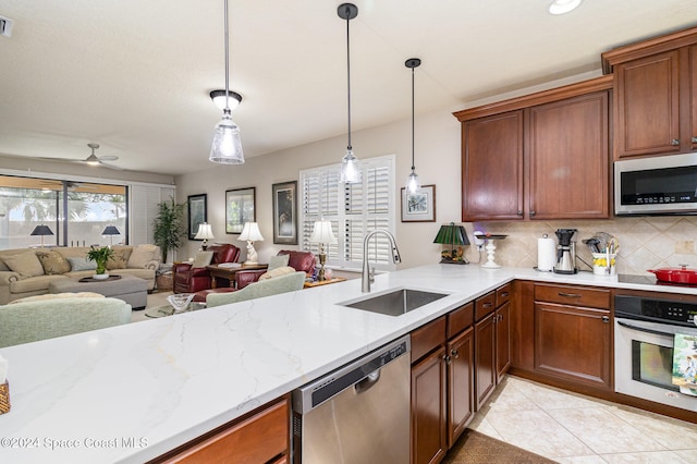 kitchen with decorative backsplash, hanging light fixtures, ceiling fan, appliances with stainless steel finishes, and sink