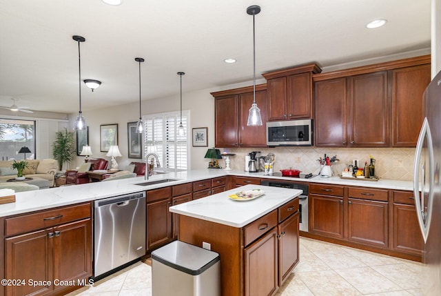 kitchen featuring kitchen peninsula, hanging light fixtures, stainless steel appliances, and sink