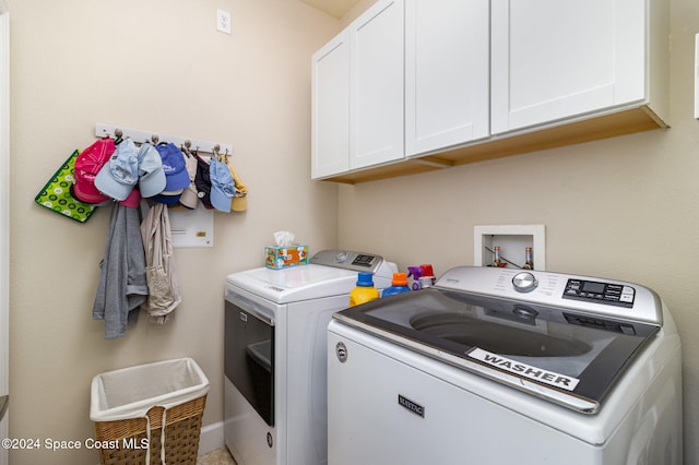 clothes washing area with washing machine and clothes dryer and cabinets