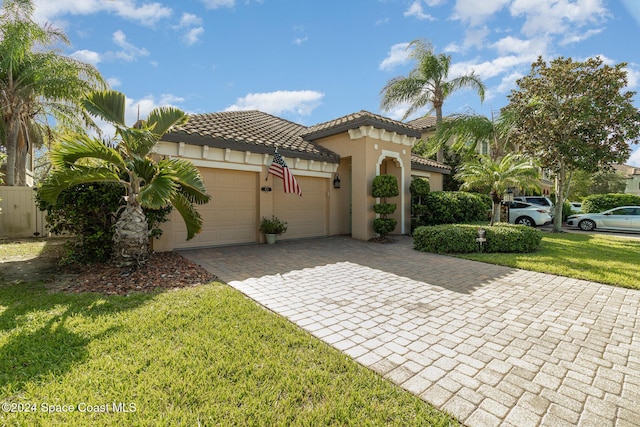 mediterranean / spanish-style house with a front lawn, a garage, stucco siding, decorative driveway, and a tiled roof
