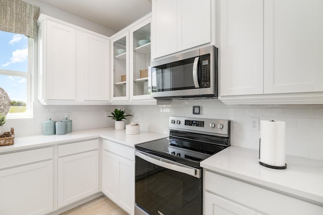 kitchen with white cabinetry, stainless steel appliances, a healthy amount of sunlight, and tasteful backsplash