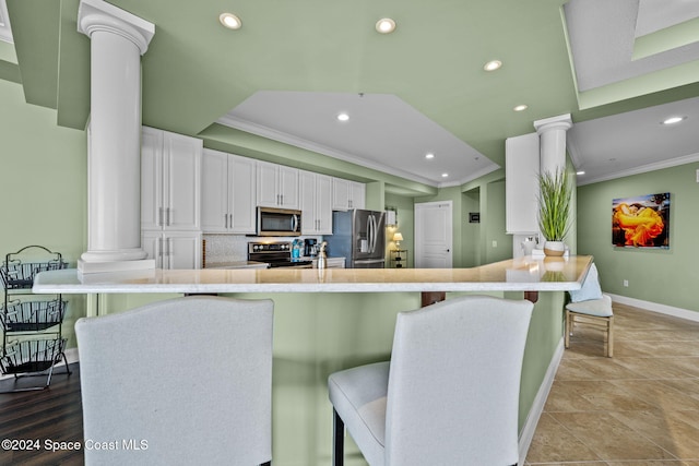 kitchen featuring kitchen peninsula, white cabinets, stainless steel appliances, and a breakfast bar