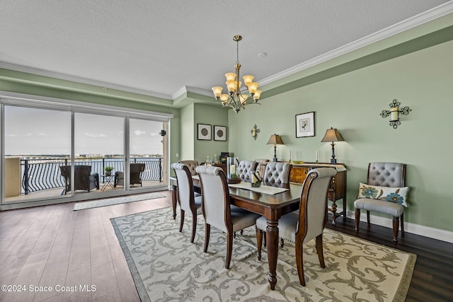 dining space with an inviting chandelier, crown molding, wood-type flooring, and a textured ceiling