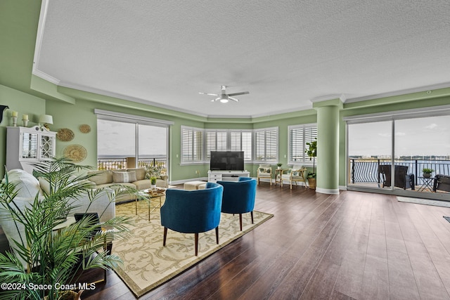 living room featuring dark wood-type flooring, ceiling fan, crown molding, and a textured ceiling