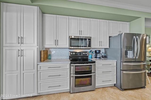 kitchen with white cabinetry, stainless steel appliances, decorative backsplash, and ornamental molding