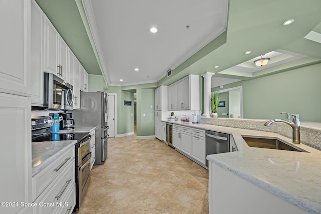 kitchen with sink, decorative columns, white cabinetry, stainless steel appliances, and light stone counters