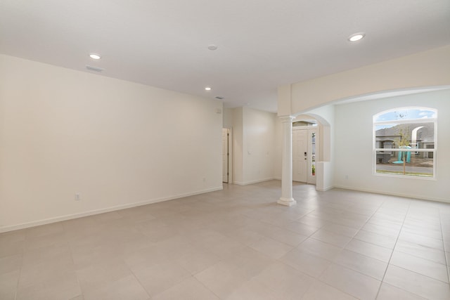 unfurnished room with decorative columns, arched walkways, baseboards, and recessed lighting