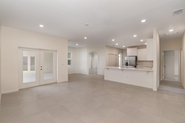 unfurnished living room with french doors and light tile patterned flooring