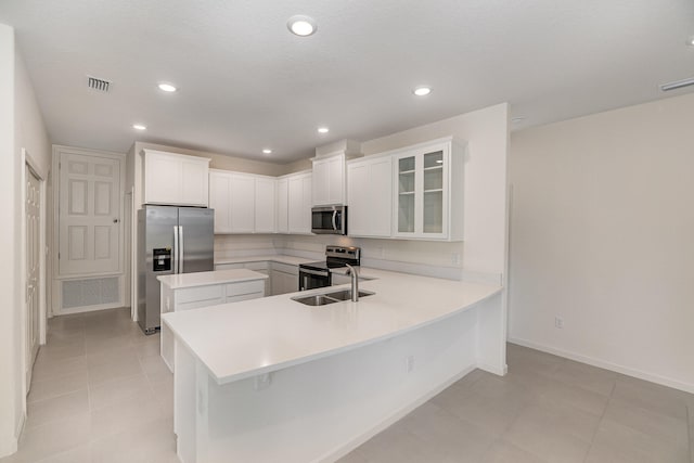 kitchen with kitchen peninsula, appliances with stainless steel finishes, a kitchen breakfast bar, sink, and white cabinetry