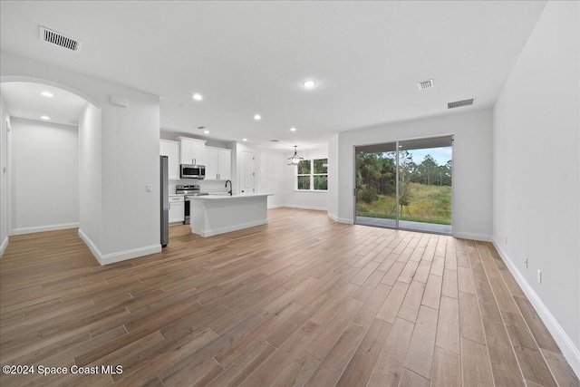 unfurnished living room featuring a chandelier, light hardwood / wood-style floors, and sink