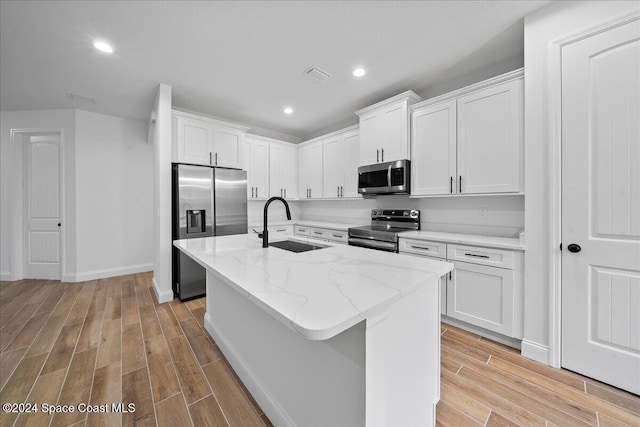 kitchen with white cabinets, appliances with stainless steel finishes, and light hardwood / wood-style flooring