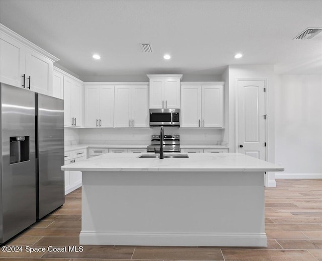 kitchen featuring white cabinets, an island with sink, and appliances with stainless steel finishes