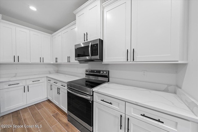 kitchen featuring light stone counters, wood-type flooring, white cabinetry, and stainless steel appliances