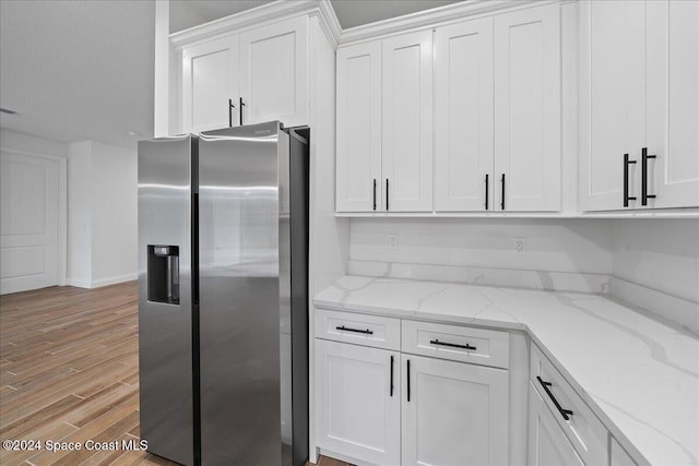 kitchen featuring white cabinetry, light stone countertops, light wood-type flooring, and stainless steel refrigerator with ice dispenser