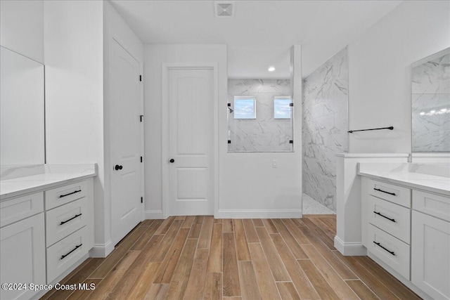 bathroom featuring tiled shower, wood-type flooring, and vanity