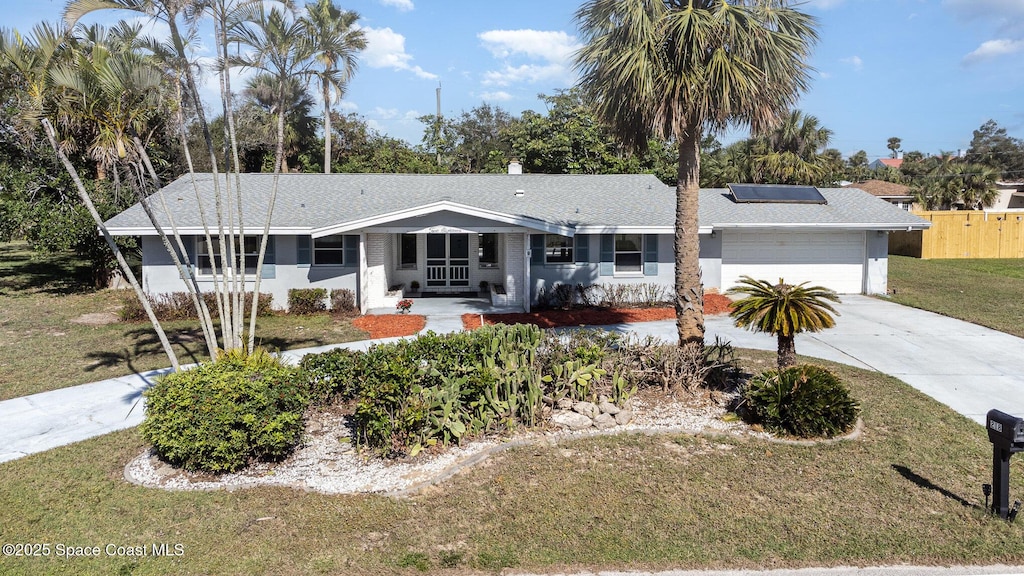 ranch-style house with solar panels, a front lawn, and a garage