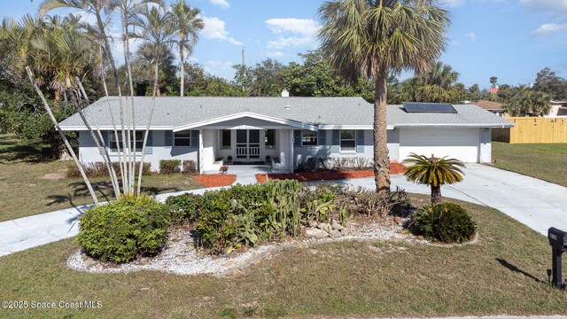 ranch-style house featuring solar panels, a front lawn, and a garage