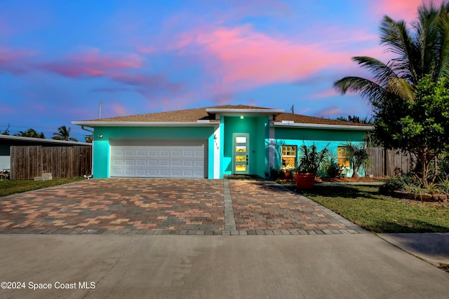 view of front of property featuring decorative driveway, an attached garage, stucco siding, and fence